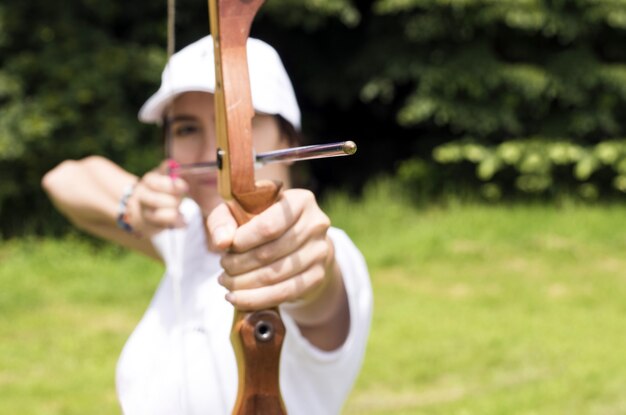 Blurred shot of a female archer holding a wooden bow and aiming at target
