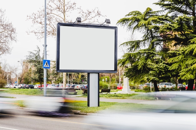 Blurred vehicle passing by the blank billboard on the road