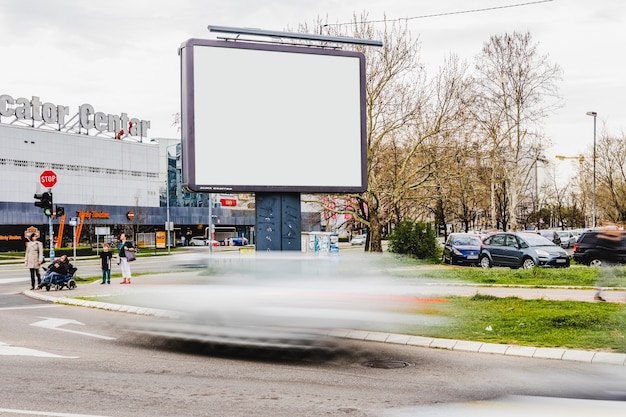 Размытое транспортное средство, проходящее мимо пустой рекламный щит на дороге