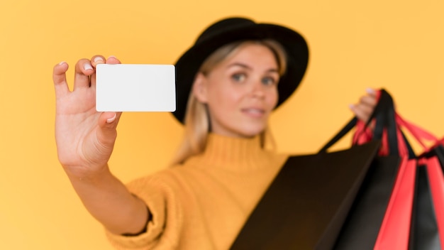 Blurred woman holding copy space card and shopping bags