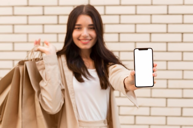 Free photo blurred woman showing copy space mobile phone