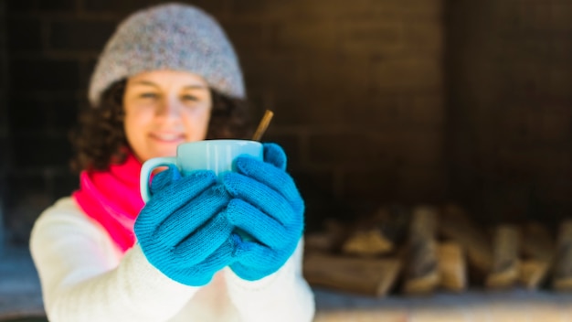 Blurred woman showing mug of hot beverage