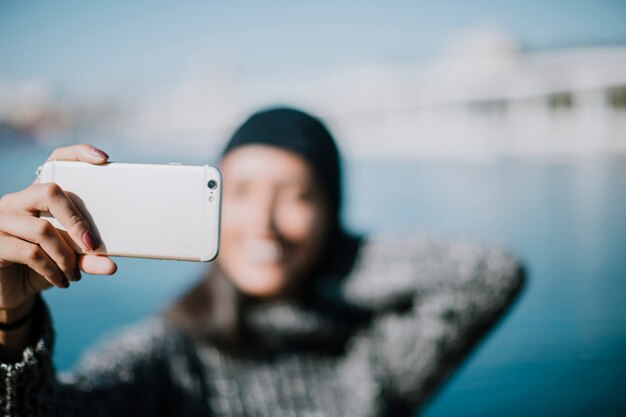Blurred woman taking selfie with water in background