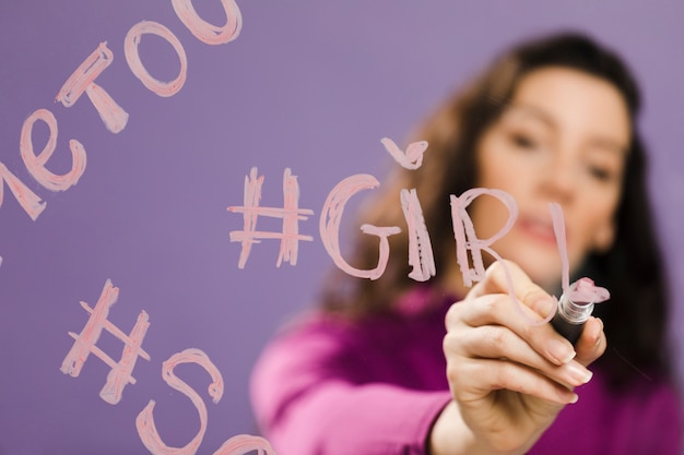 Blurred woman writing "girl" on transparent glass
