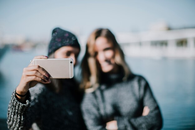 Blurred women taking selfie with water in background