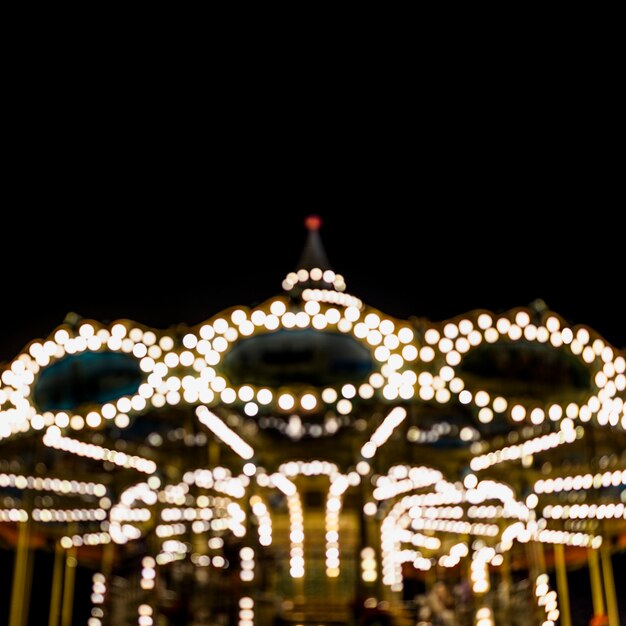 A blurry illuminated carousel in the amusement park at night