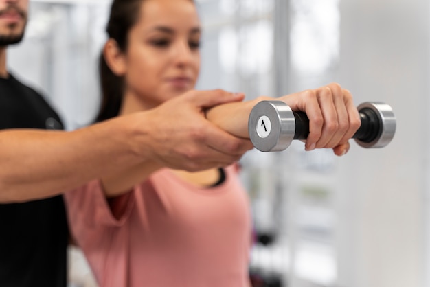 Blurry woman exercising with dumbbell close up