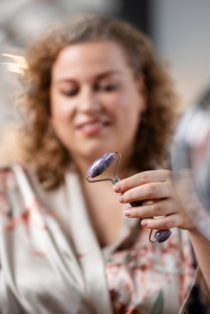 Foto gratuita donna sfocata che massaggia il viso con un colpo medio di gua sha