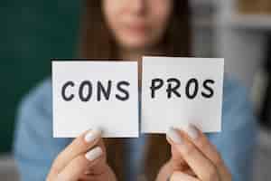 Free photo blurry woman holding cons and pros post its