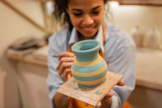 Blurry woman painting clay pot