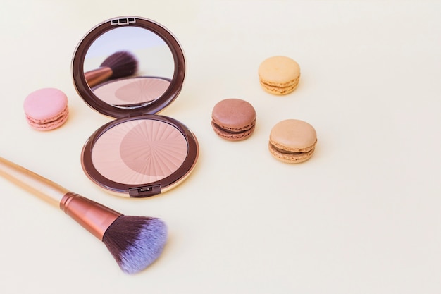 Free photo blusher with macaroon and makeup brush on beige background