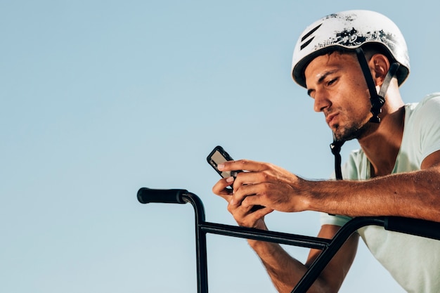 Bmx rider looking at his phone medium shot