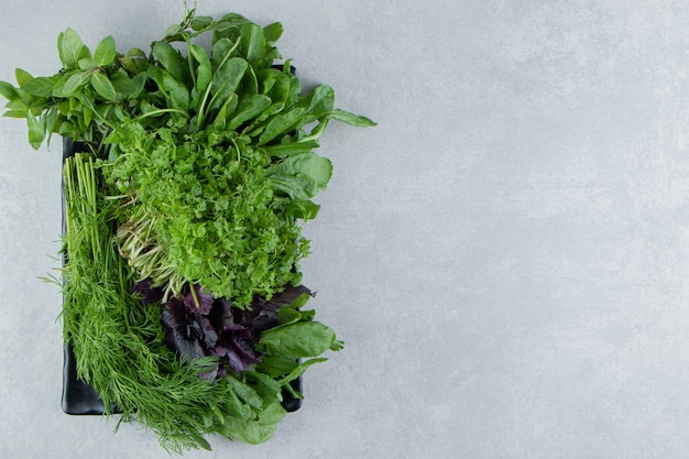 Board full of different greenery , on the marble background