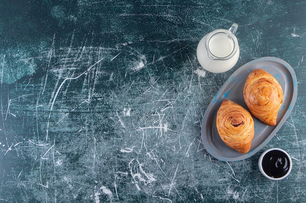 A board of rolls of puff pastry with a glass pitcher of fresh milk. 