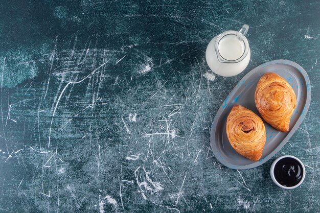 A board of rolls of puff pastry with a glass pitcher of fresh milk. 