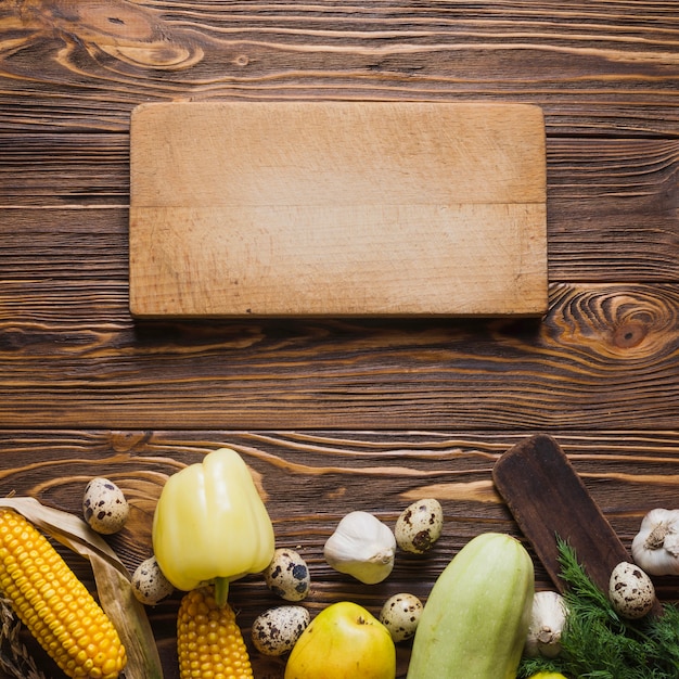 Board and vegetables on wooden surface