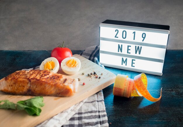 Board with 2019 new me inscription with roasted salmon on table