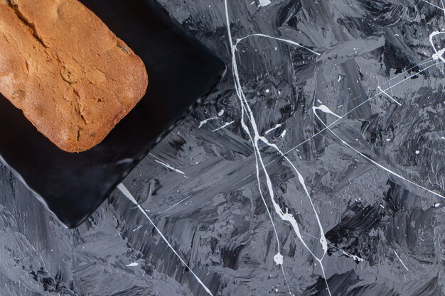 A board with fresh baked raisin bread placed on a marble background. 