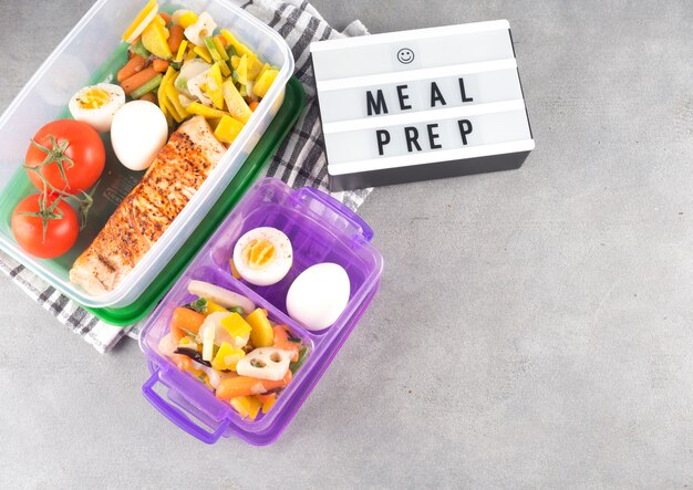 Board with Meal prep inscription near food in containers