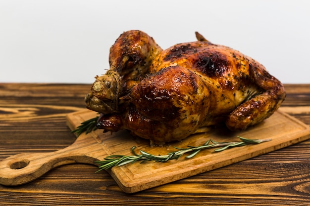 Board with roasted chicken on table