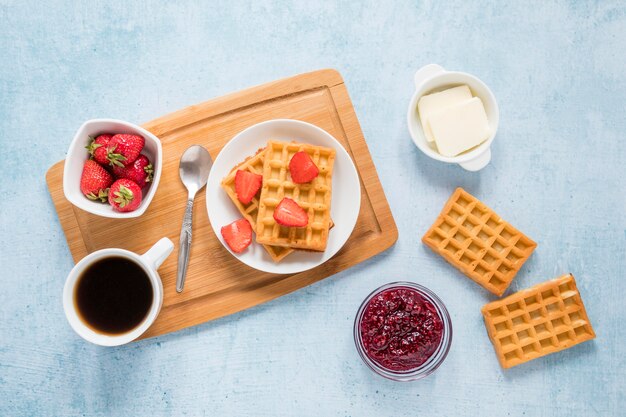 Board with waffles and fruits on table