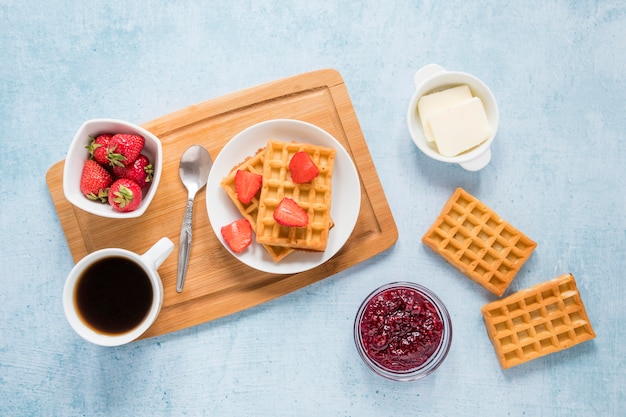 Board with waffles and fruits on table