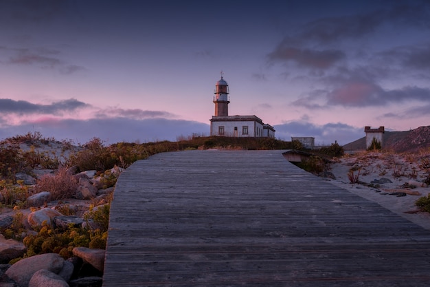 Boardwalk leading to the Larino Lighthouse during the sunset in the evening in Spain