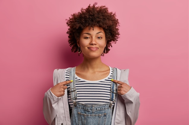 Foto gratuita la superba donna afroamericana riccia ha ottenuto un buon lavoro, indica se stessa