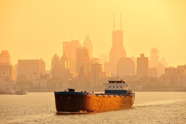 Boat in Huangpu River with Shanghai urban architecture at sunset