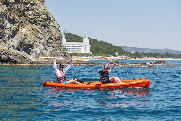 晴れた日に崖の近くでカヤックをするボート。静かな湾でのカヤック。素晴らしい景色。旅行、スポーツコンセプト。ライフスタイル。幸せな家族。