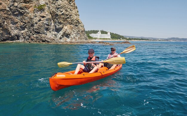 Boat kayaking near cliffs on a sunny day. Kayaking in a quiet bay. Amazing views. Travel, sports concept. Lifestyle. A happy family.