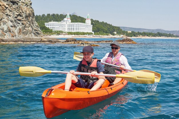 晴れた日に崖の近くでカヤックをするボート。静かな湾でのカヤック。素晴らしい景色。旅行、スポーツコンセプト。ライフスタイル。幸せな家族。