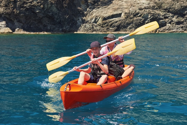 Boat kayaking near cliffs on a sunny day. Kayaking in a quiet bay. Amazing views. Travel, sports concept. Lifestyle. A happy family.