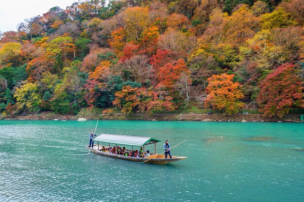 ボートマンが川でボートをパントします。京都の川沿いの秋の季節の嵐山。