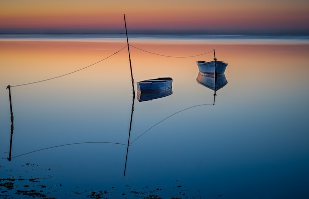 Boats floating ob the water under the colorful sky