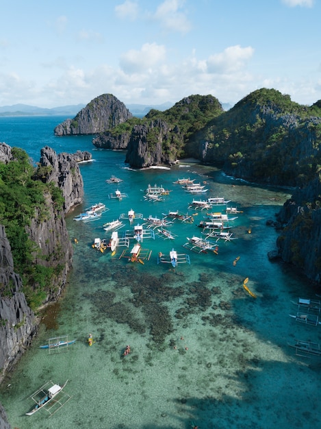 Boats on the ocean surrounded by mountains under the cloudy sky