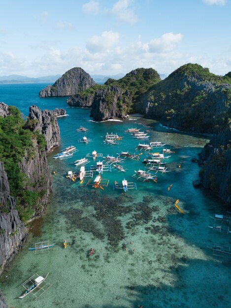 Boats on the ocean surrounded by mountains under the cloudy sky