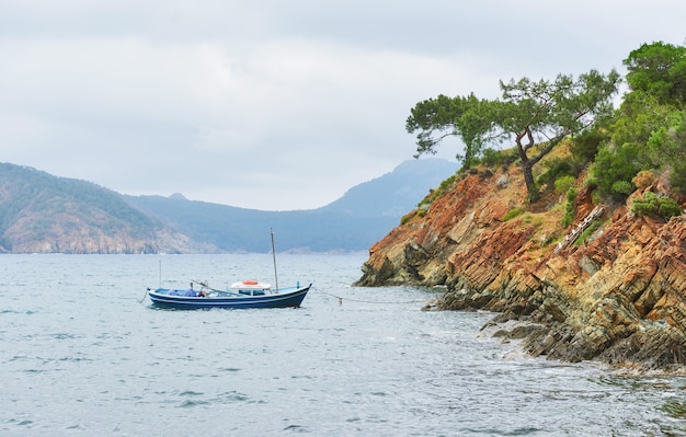 Лодки плывут в спокойной голубой морской воде возле гор в Турции.