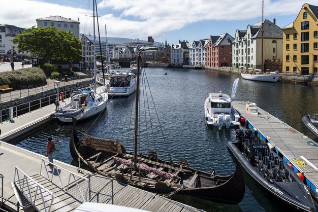 Boats on a wide water canal surrounded by colorful buildings in Alesund, Norway