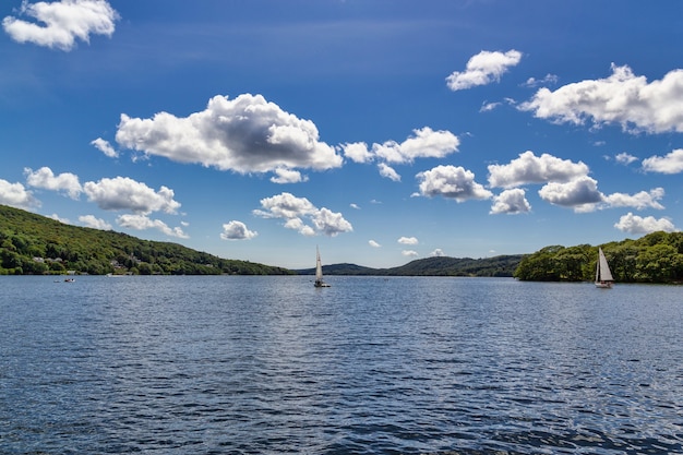 Лодки на озере Уиндермир с маленькими пушистыми облаками над головой