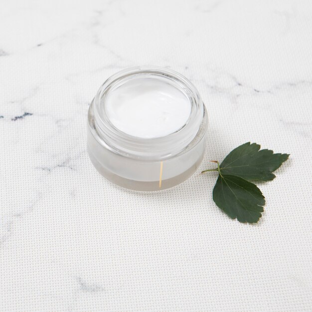 Body butter with leaves on marble background