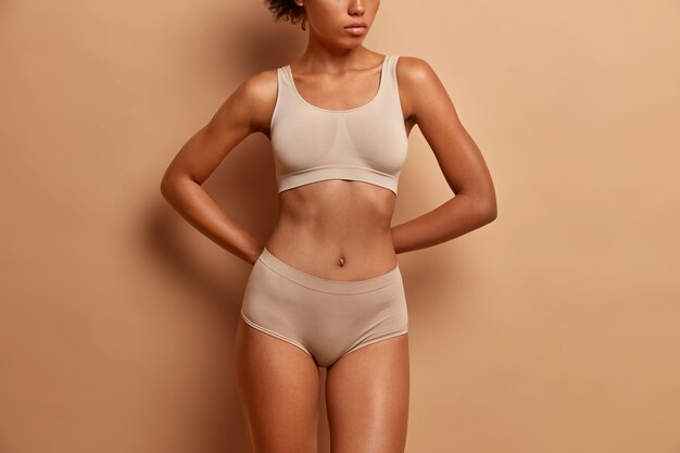 Body care concept. dark skinned woman wears lingerie ha flat belly and slender legs.