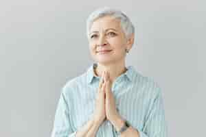 Free photo body language. positive charming mature grandmother clapping hands, smiling, proud of her talented grandson. elegant gray haired female posing isolated with happy smile, having touched look