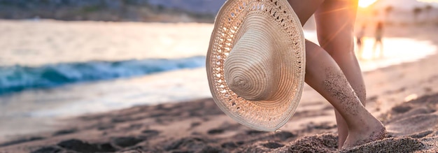 Foto gratuita parte del corpo piedi di una donna in piedi sulla spiaggia al tramonto con un cappello