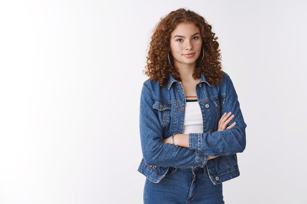 Body-positivity skincare self-care concept. Attractive european girl freckles acne prone skin hold hands crossed chest look camera seriously confident, standing white background professional pose