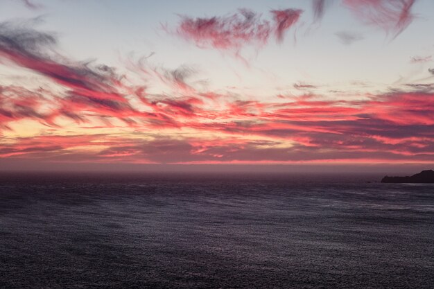 Body of water under cloudy sky during sunset