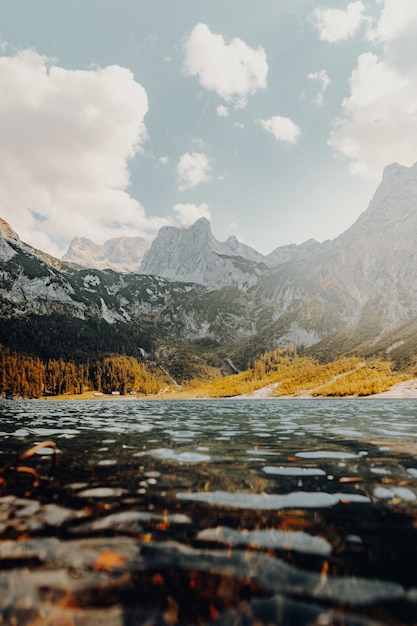 Specchio d'acqua che osserva la montagna sotto il cielo bianco e blu durante il giorno