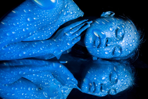 Тело женщины с голубым узором и его отражение