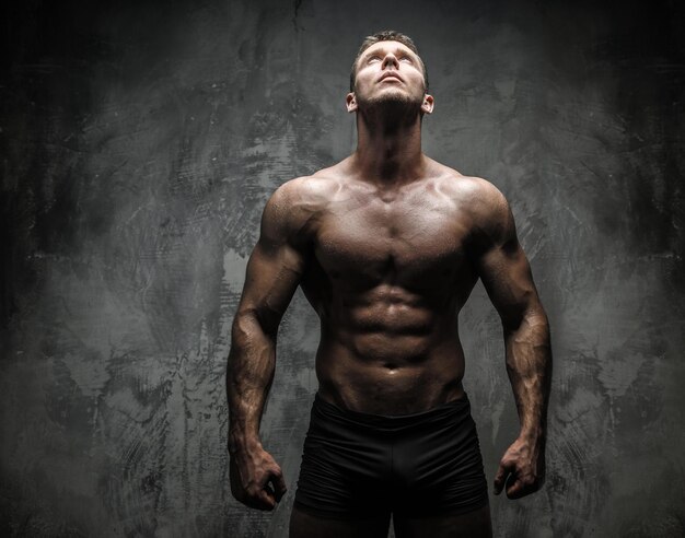 Bodybuilder posing in studio on grey background