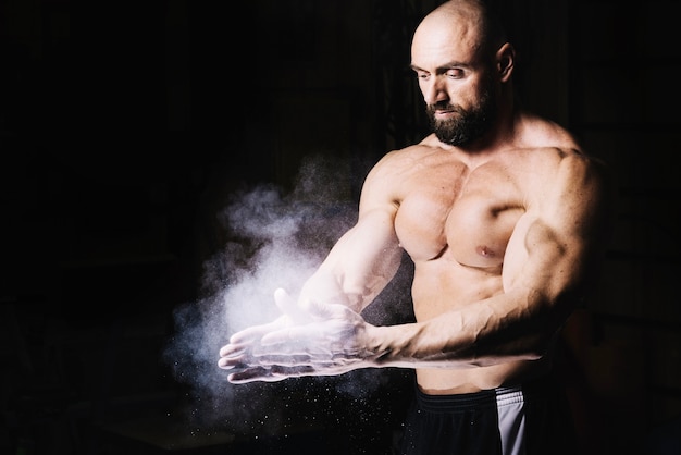 Free photo bodybuilder rubbing hands with talcum powder